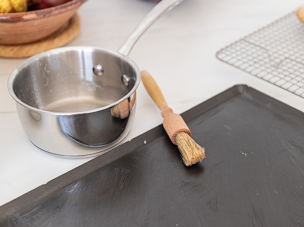 Beurrer la plaque à pâtisserie avec le reste de beurre fondu au fond de la casserole. Utiliser un pinceau. 