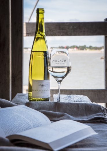 Bouteille de vin blanc de Gros-Plant et verre de vin, devant l'océan et livre ouvert