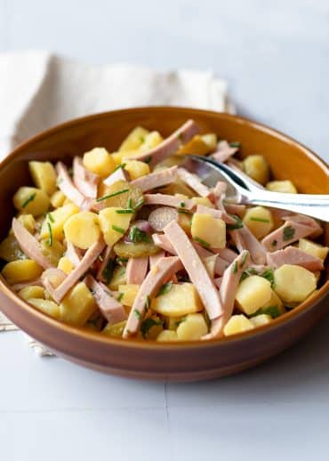 La recette de la salade alsacienne aux pommes de terre, cervelas, cornichons, herbes fraîches, vin et vinaigrette.